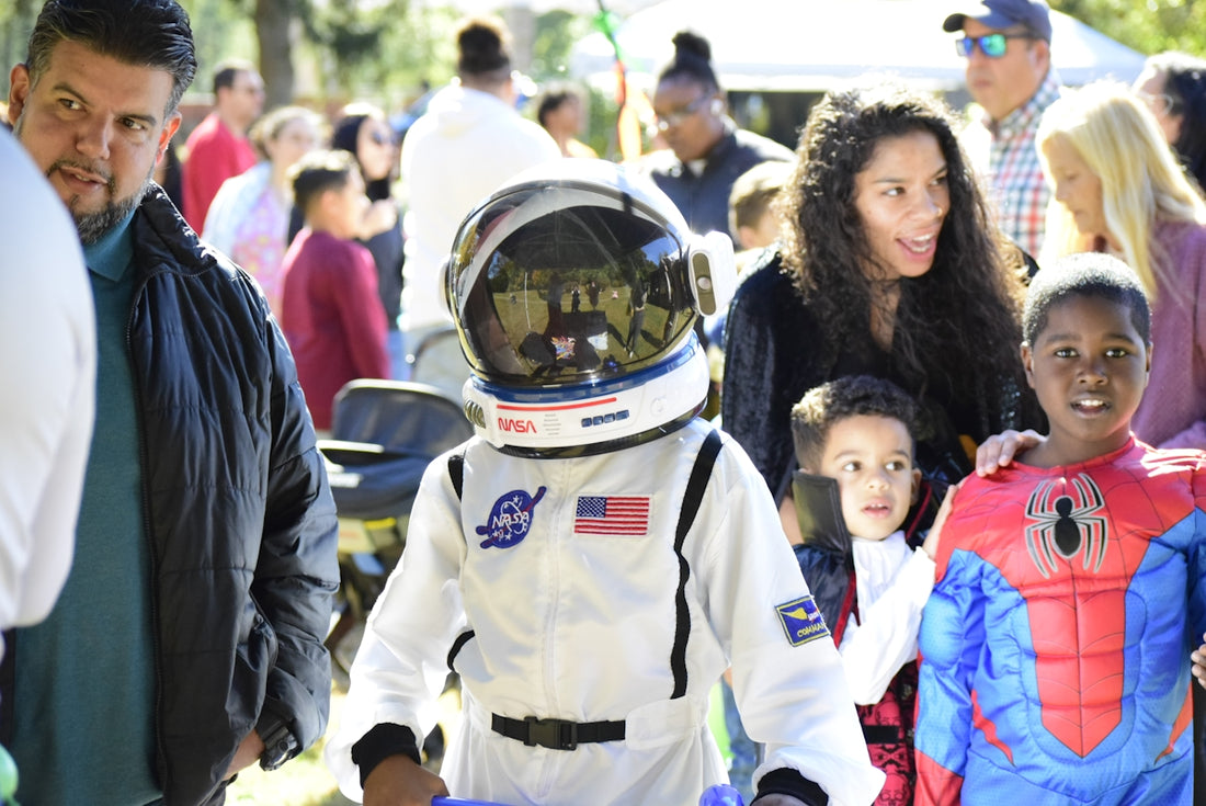 Children in astronaut and spider-man costumes at an outdoor event